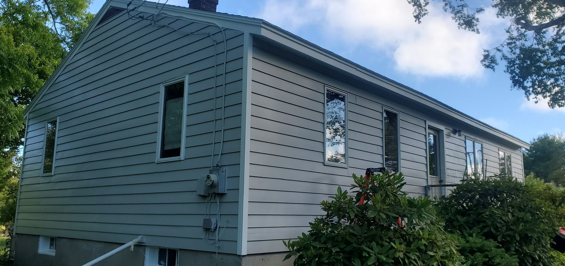 Gray house with siding and multiple windows; blue sky background.