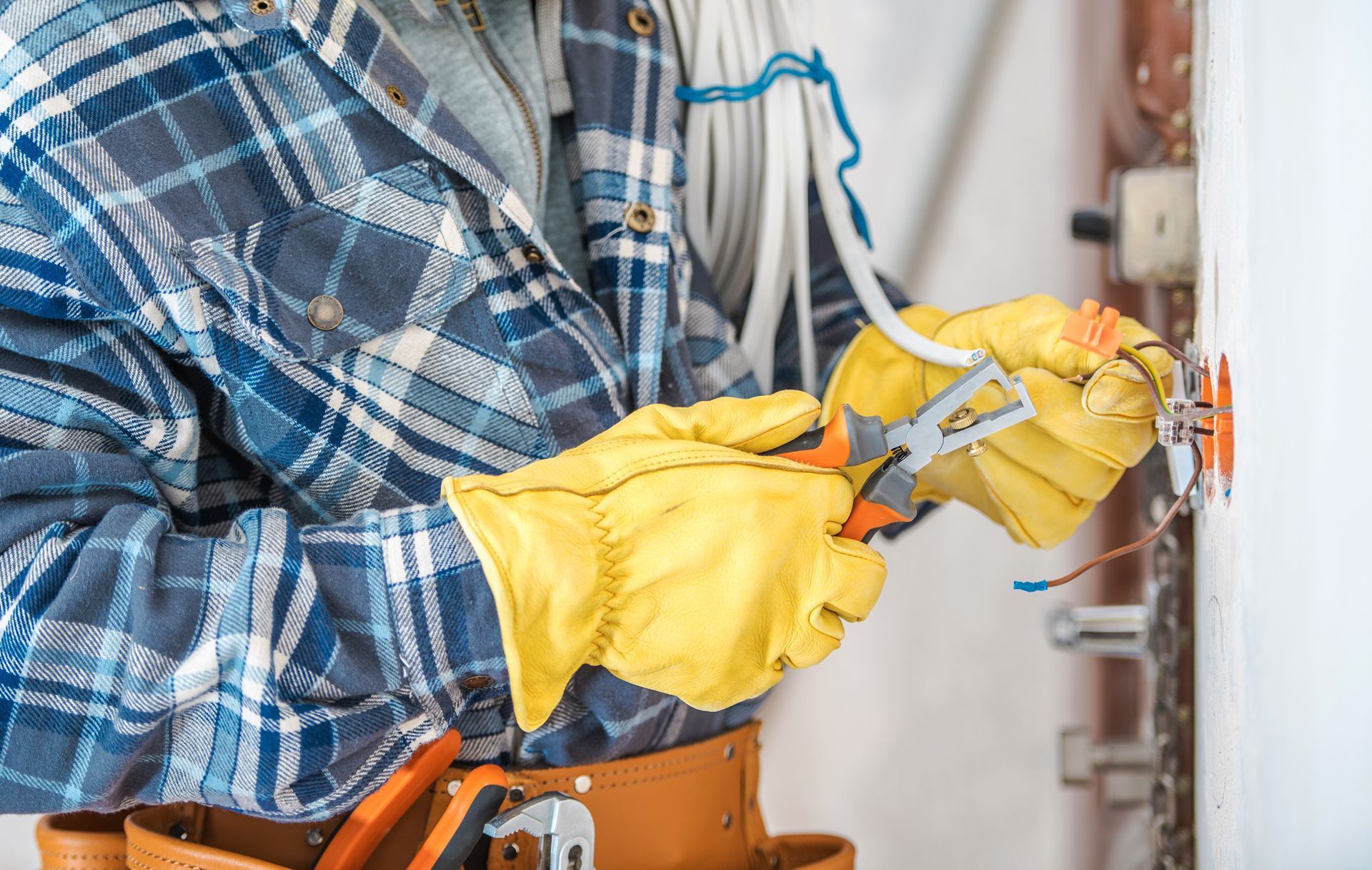 Electrician wearing gloves working on electrical wiring.