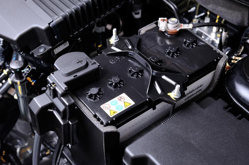 A Car Battery Is Sitting Under the Hood of A Car — Belmont Auto Electrics in Belmont, NSW