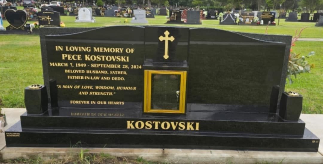 Black granite headstone with gold cross and name, 