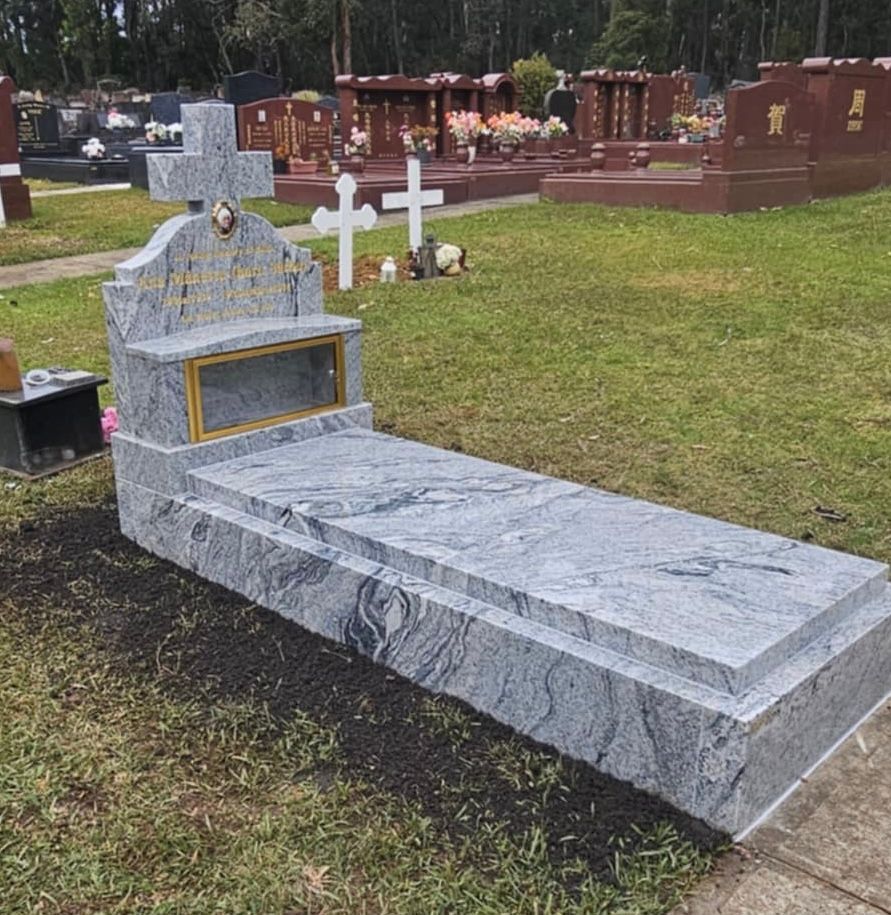 Gray granite headstone with a cross in a cemetery.