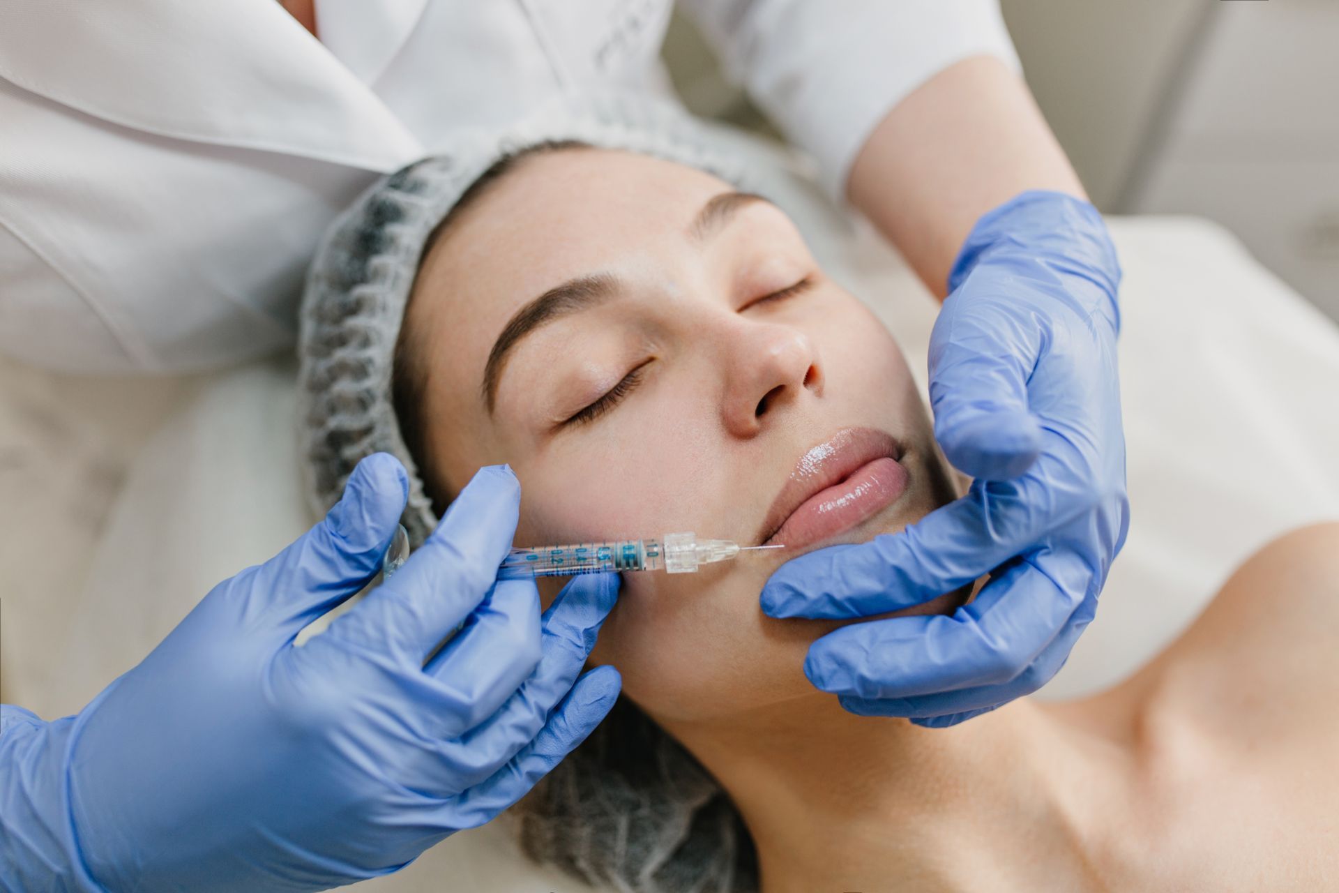 A woman is getting a botox injection in her lips.