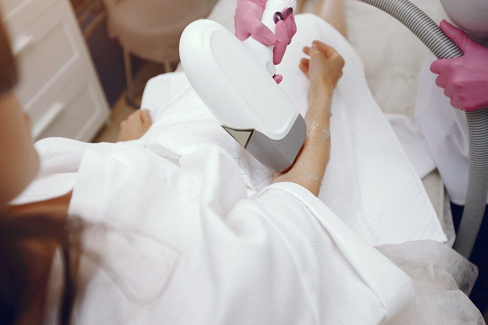 A woman is getting a laser hair removal treatment on her face.