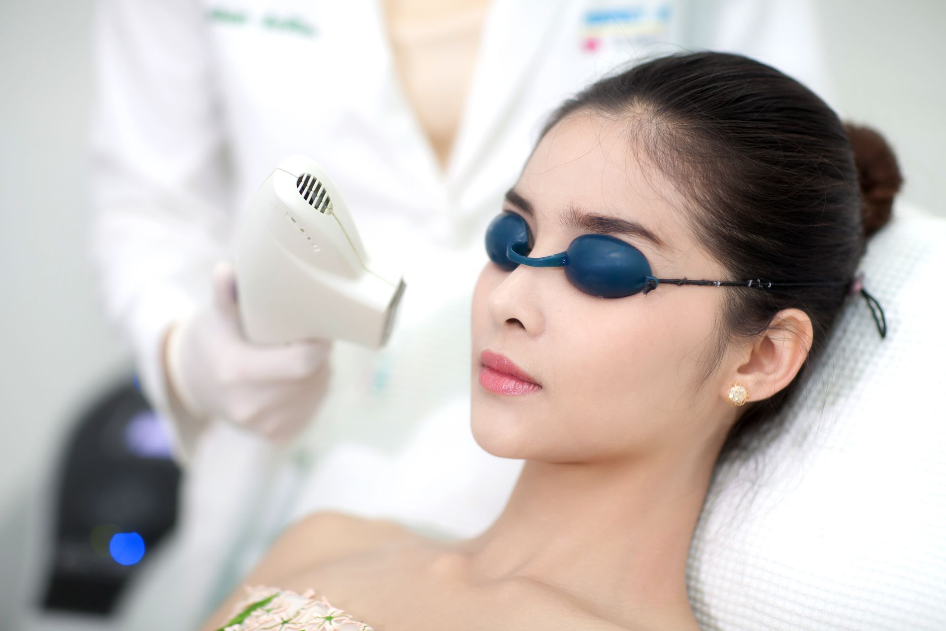 A woman is getting a laser hair removal treatment on her face.