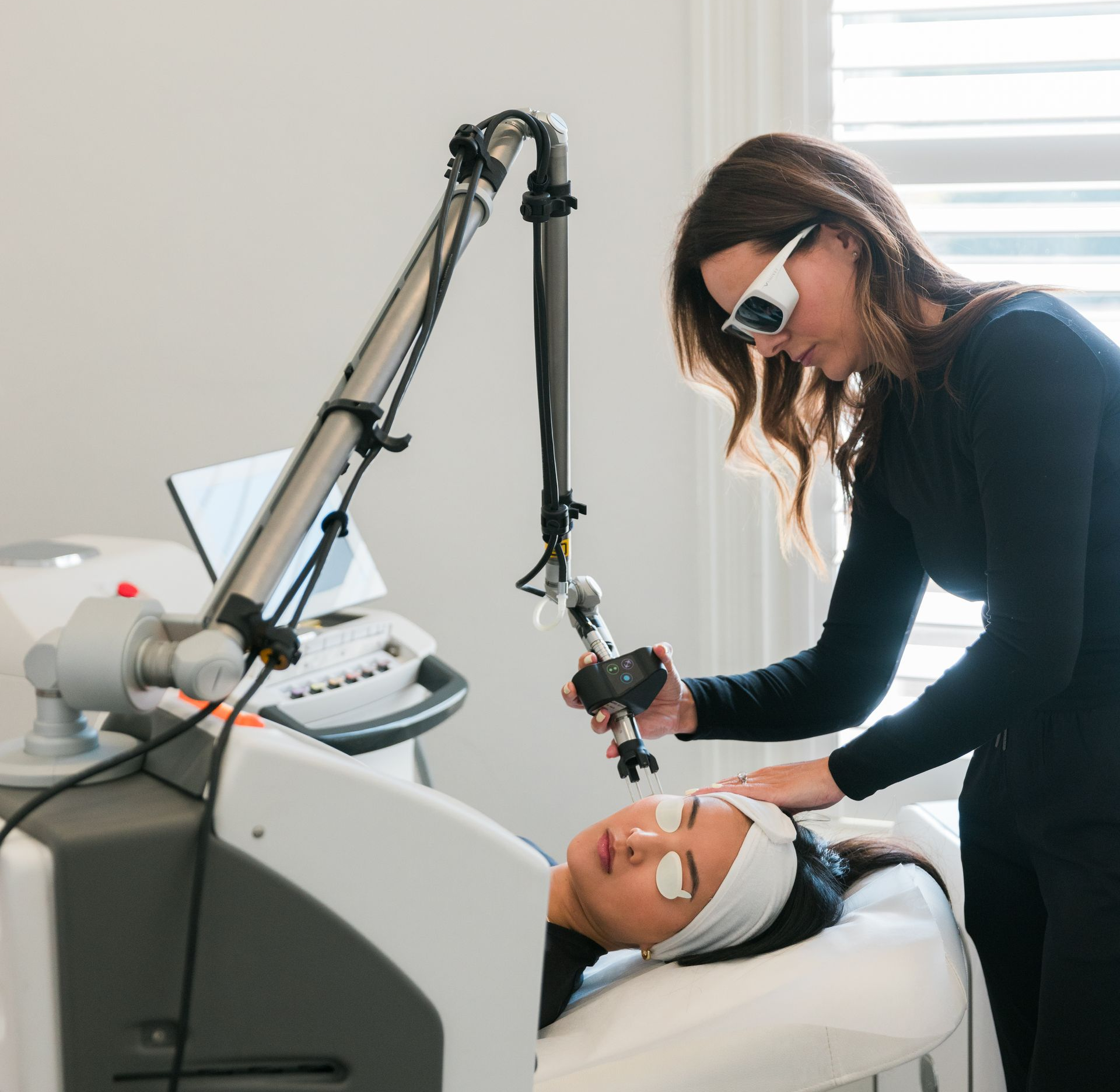 Woman holding a medical device near a machine in a medical office setting.