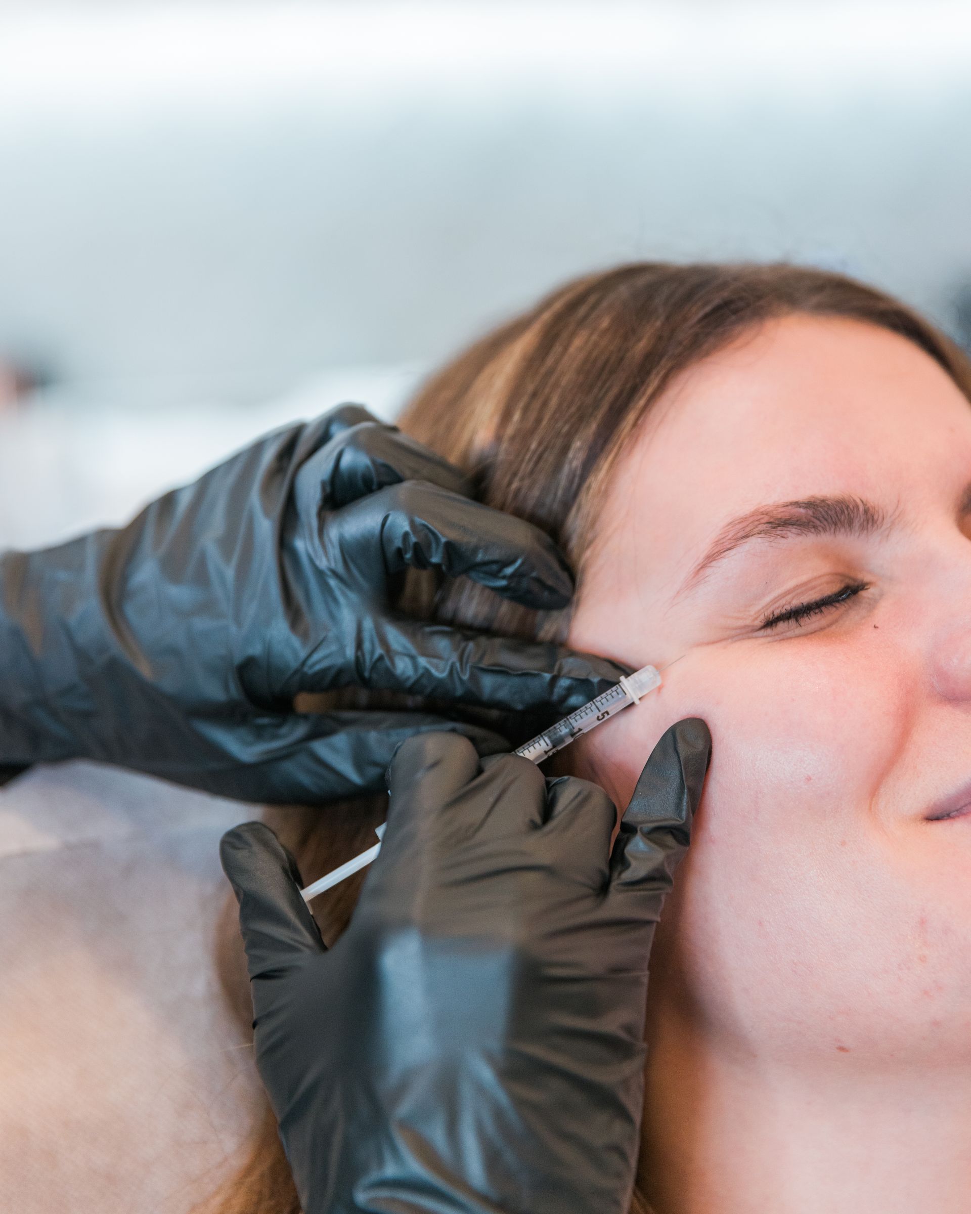 A woman is getting a botox injection in her face.