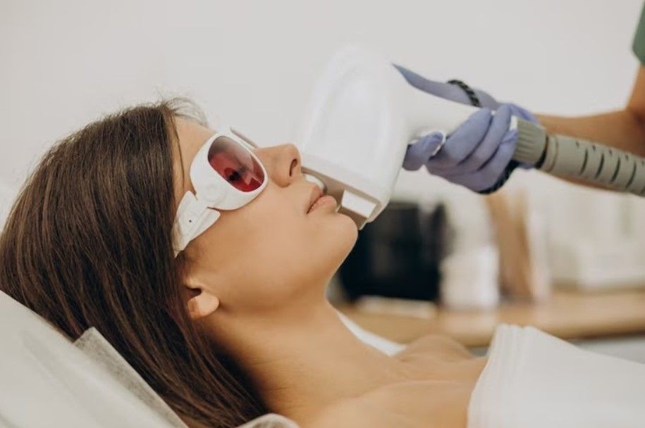 A woman is getting a laser hair removal treatment on her face.