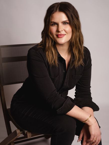 A woman in a black shirt is sitting on a chair.