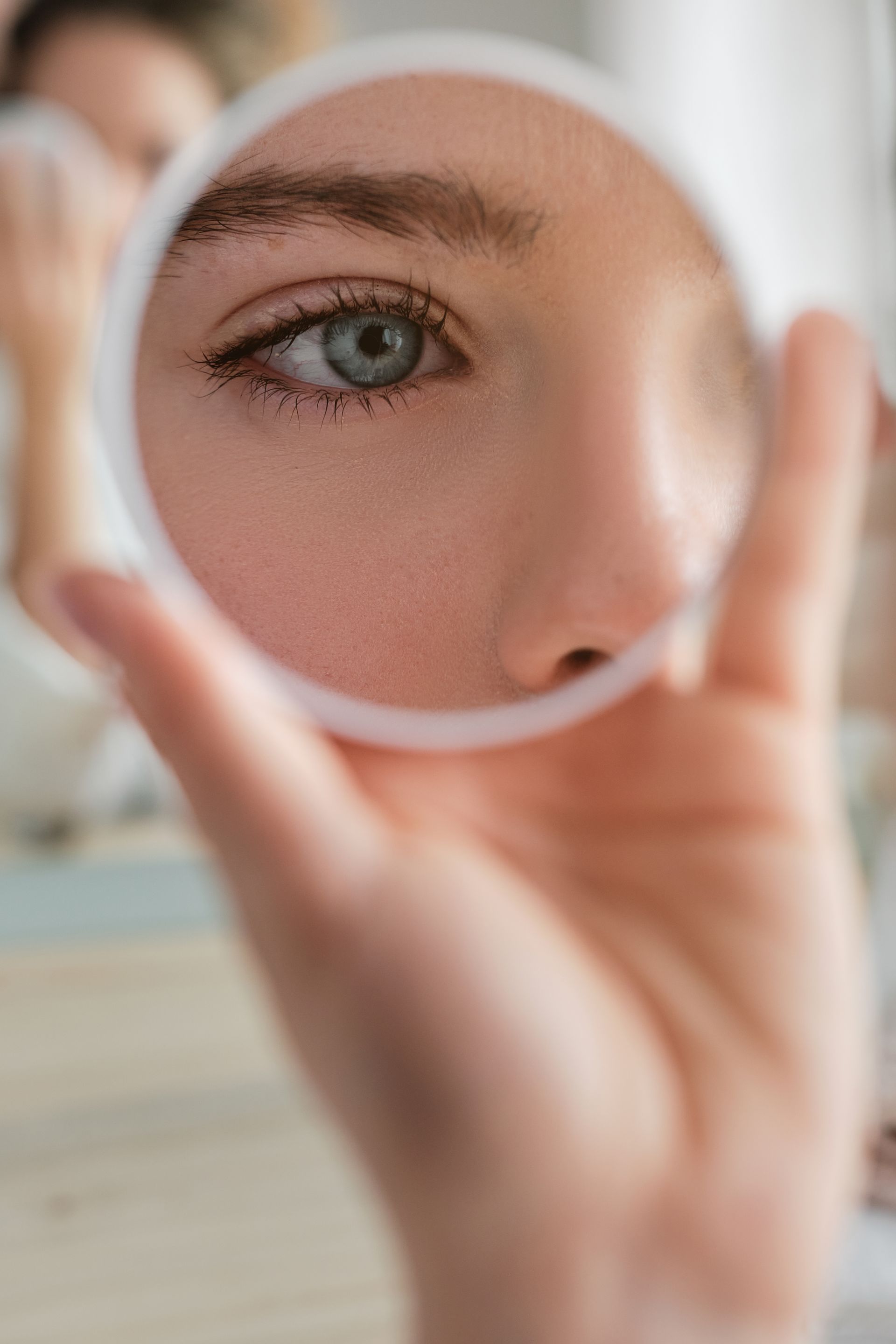 woman with round mirror looking at closeup of eye