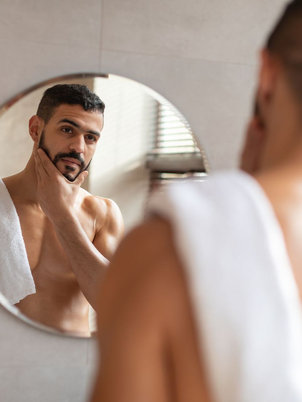 handsome man looking at jaw in mirror