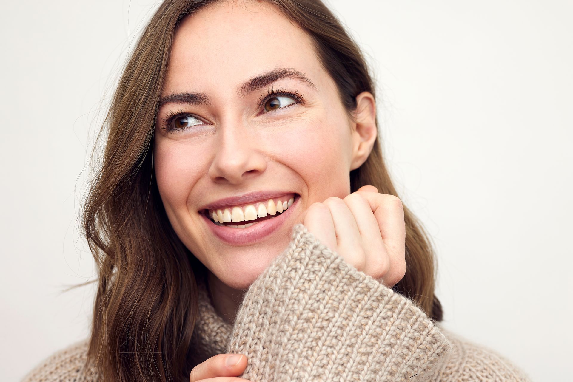 A close up of a woman wearing a sweater and smiling.