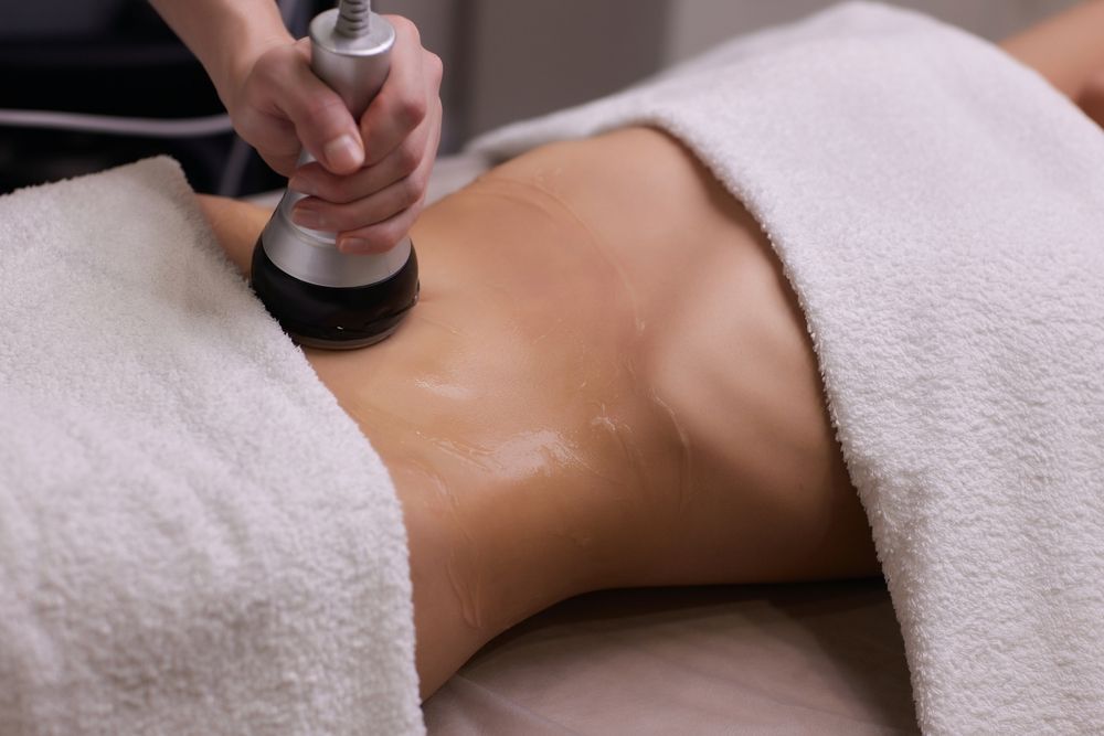 A woman is getting a cavitation treatment on her stomach.