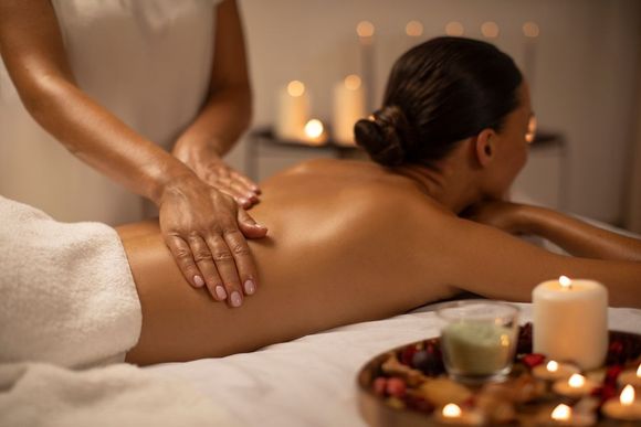 A woman is getting a massage in a spa with candles in the background.