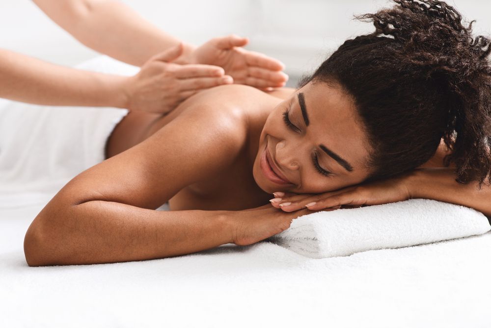 A woman is laying on a bed getting a massage.