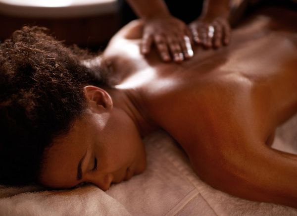 A woman is laying on a bed getting a massage.