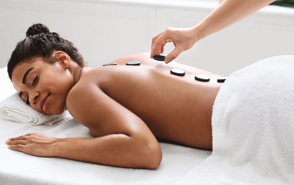 A woman is getting a hot stone massage at a spa.
