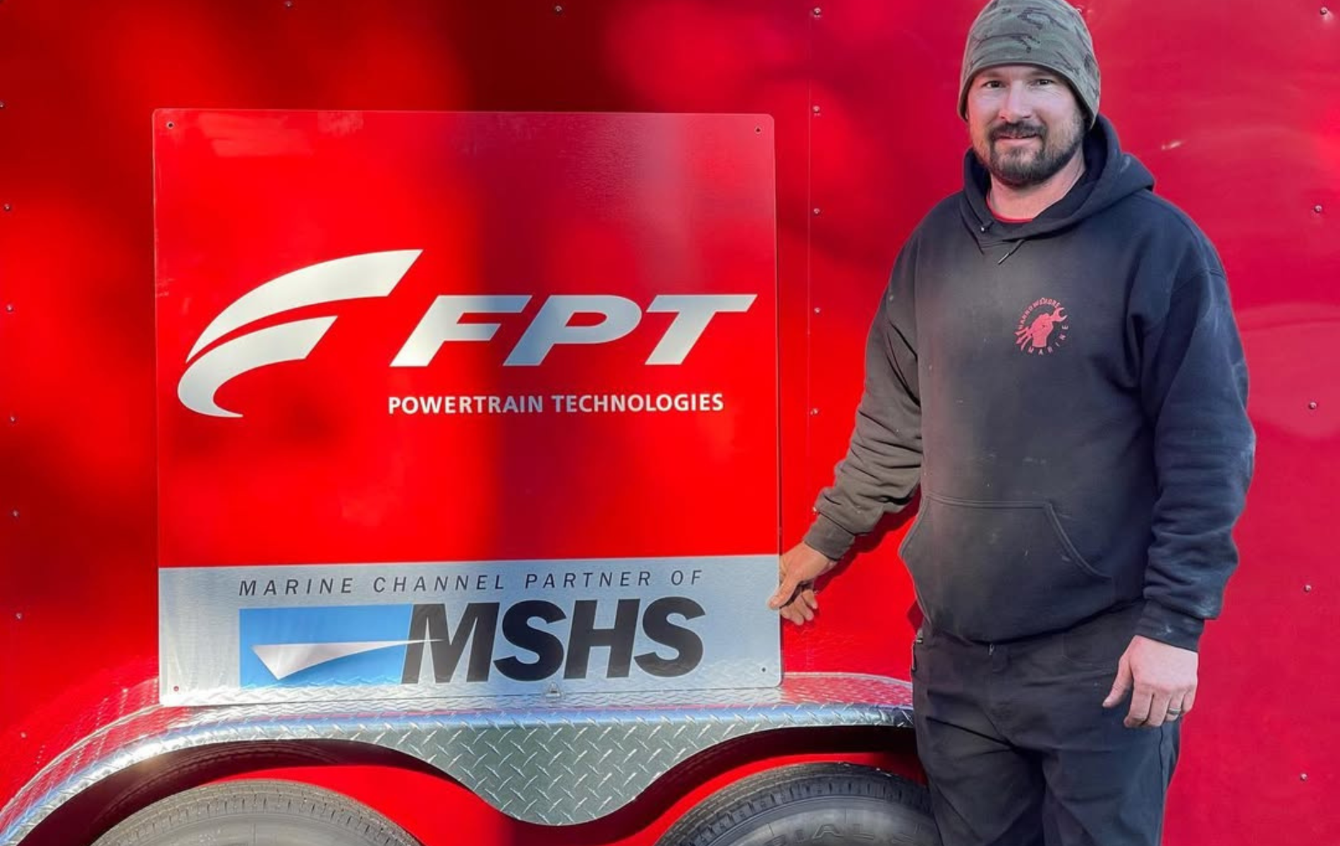 A man is standing in front of a red fpt trailer.