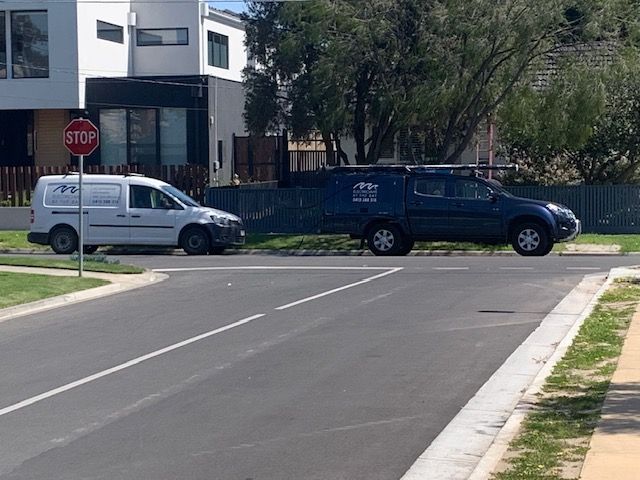 White van and blue SUV at a street corner with a stop sign in a residential area.