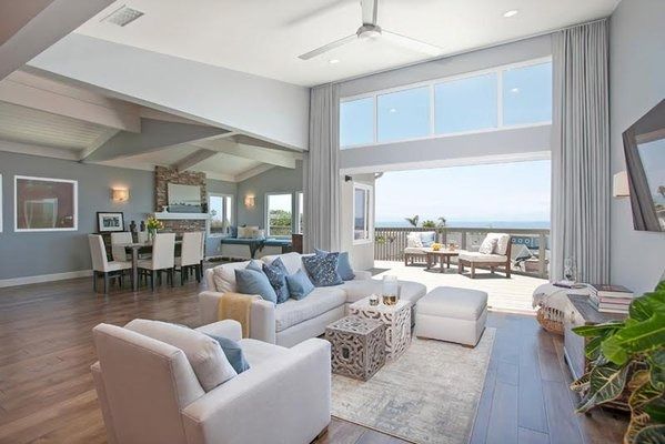Open-concept living room with a large window leading to a deck overlooking the ocean.