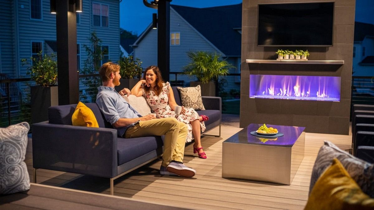 Couple on navy sofa, talking outdoors at night, with a fireplace and television.