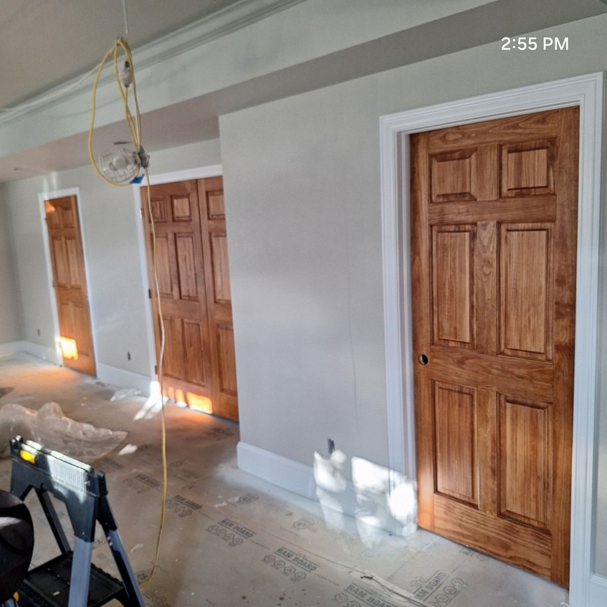Newly painted room with three wooden doors. White trim and grey walls. Construction materials on floor.