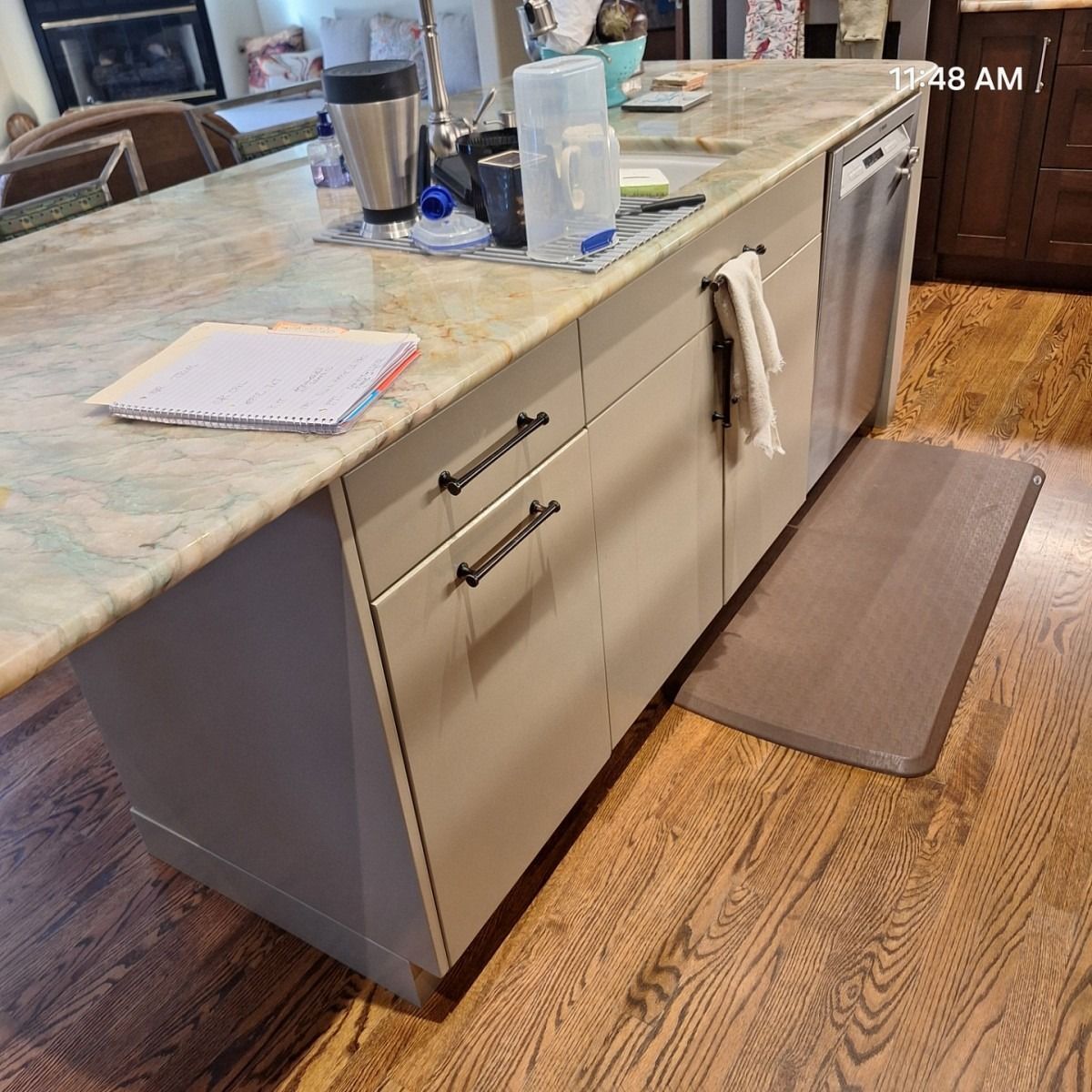 Kitchen island with cabinets, dishwasher, countertop, and a rug on a wood floor.