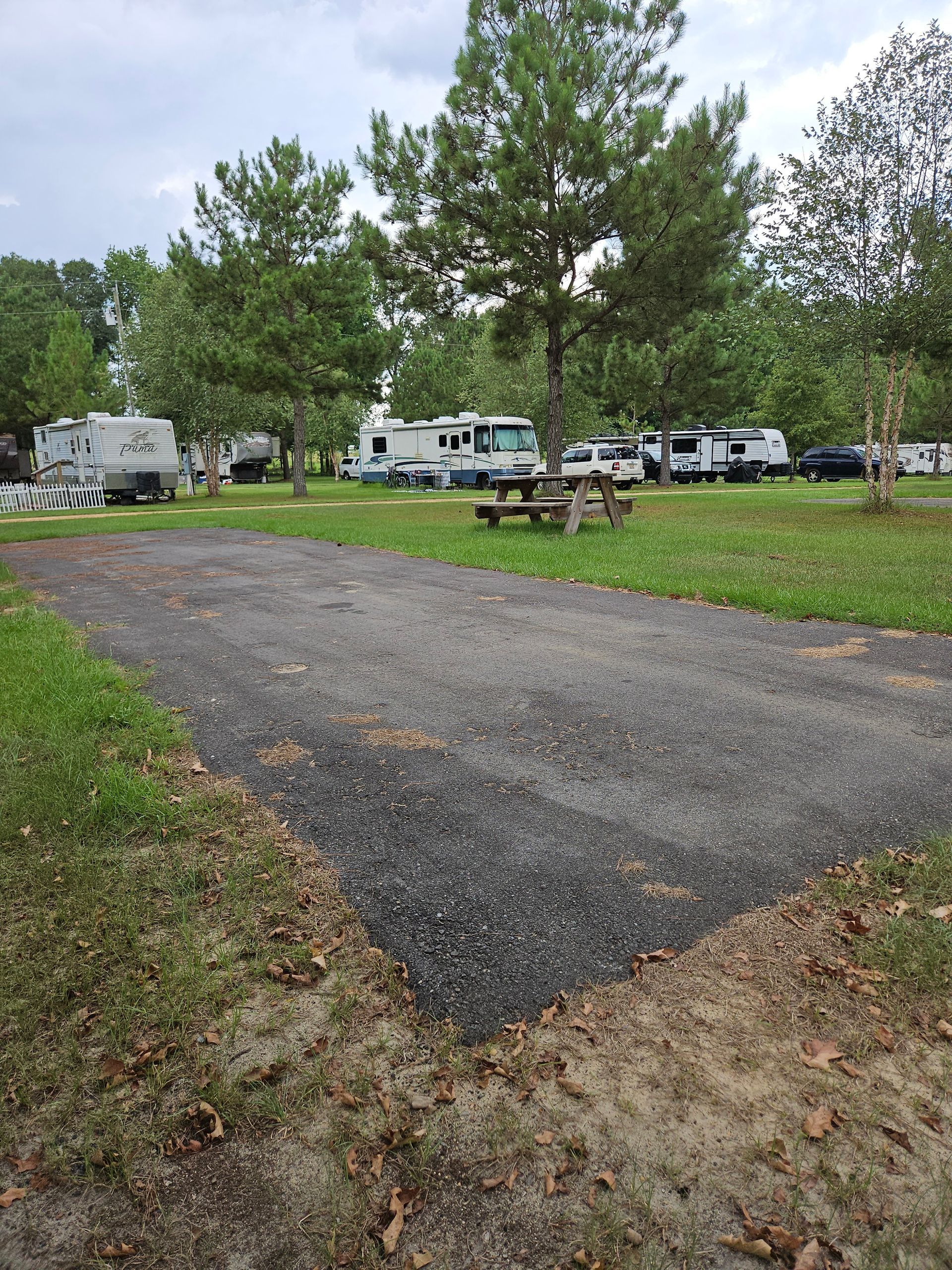 A gravel RV campsite with a picnic table; other RVs and trees in the background.