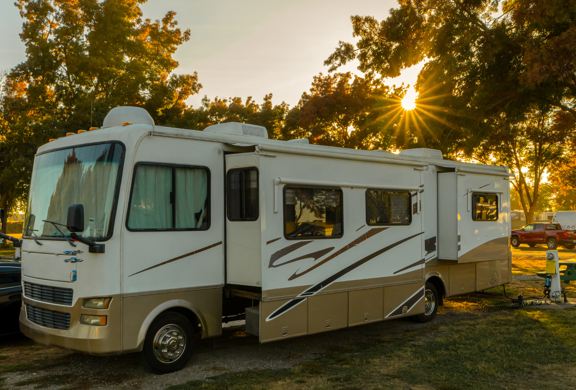 RV parked with slide-out open, bathed in golden sunset light.