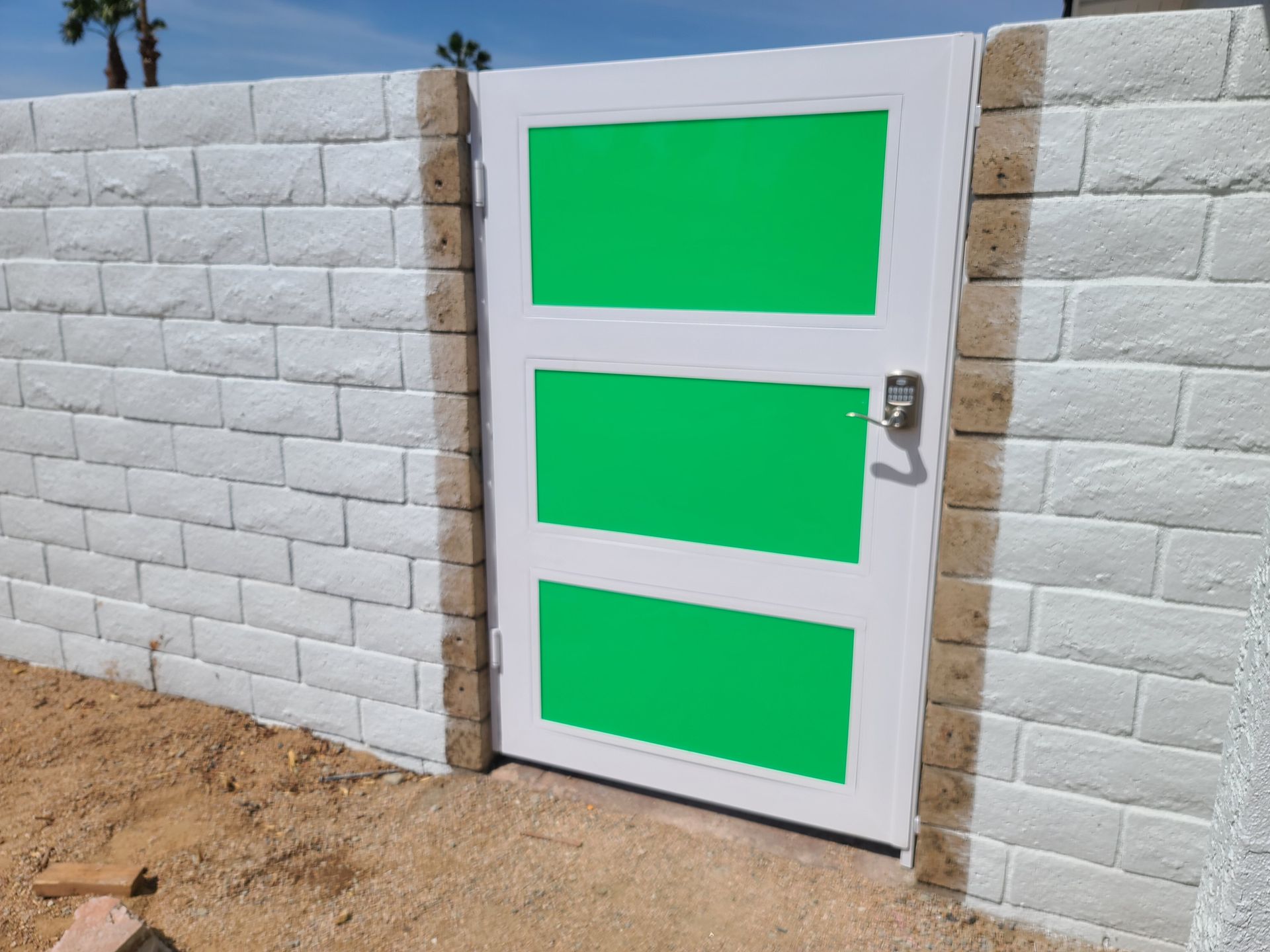 A white brick wall with a green door in the middle