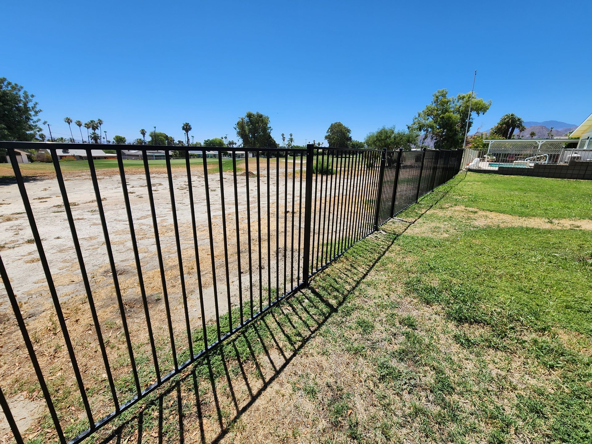 A black metal fence surrounds a grassy field.