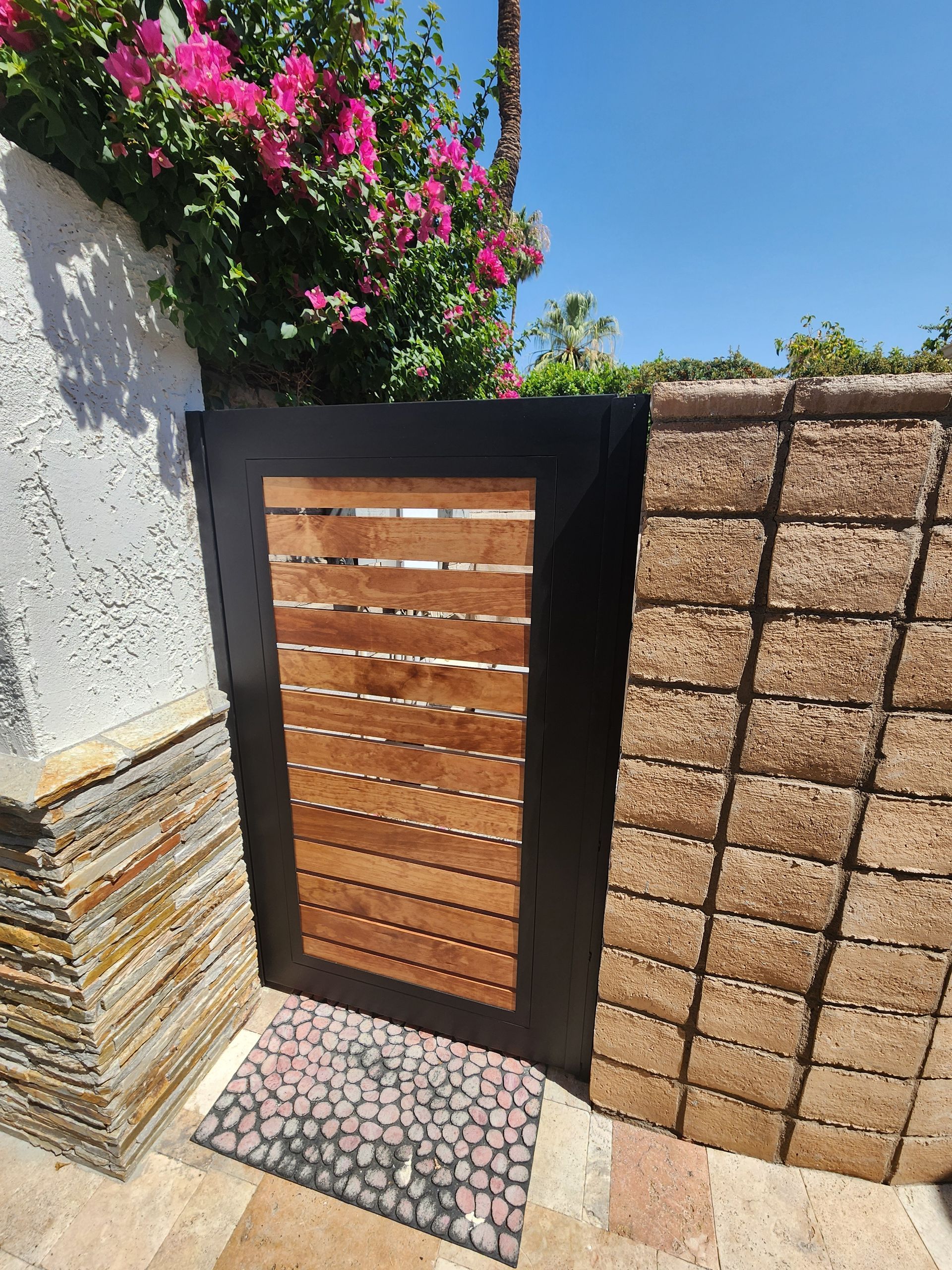 A wooden gate is sitting next to a brick wall.