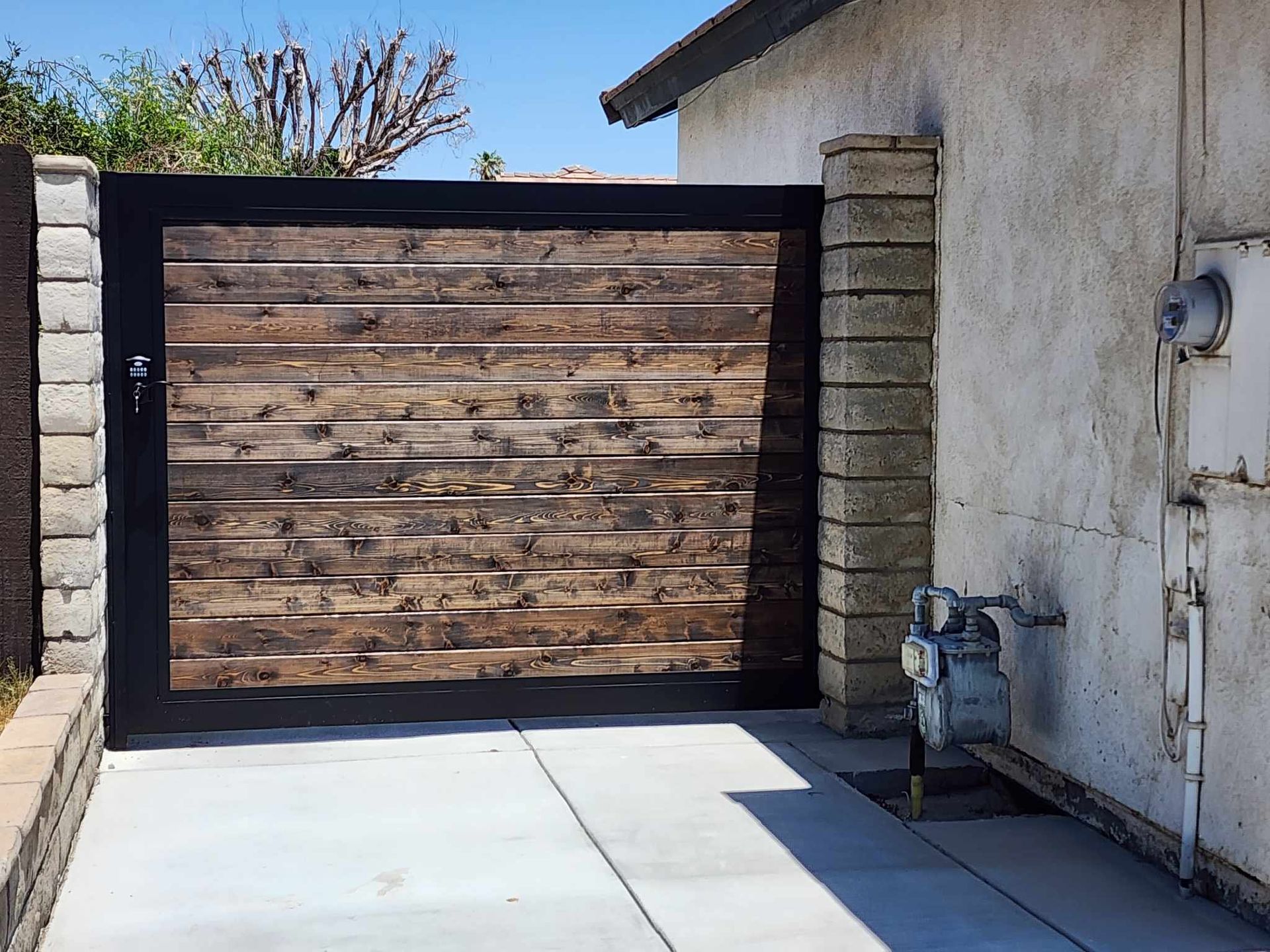 A concrete driveway with a wooden gate in front of a house