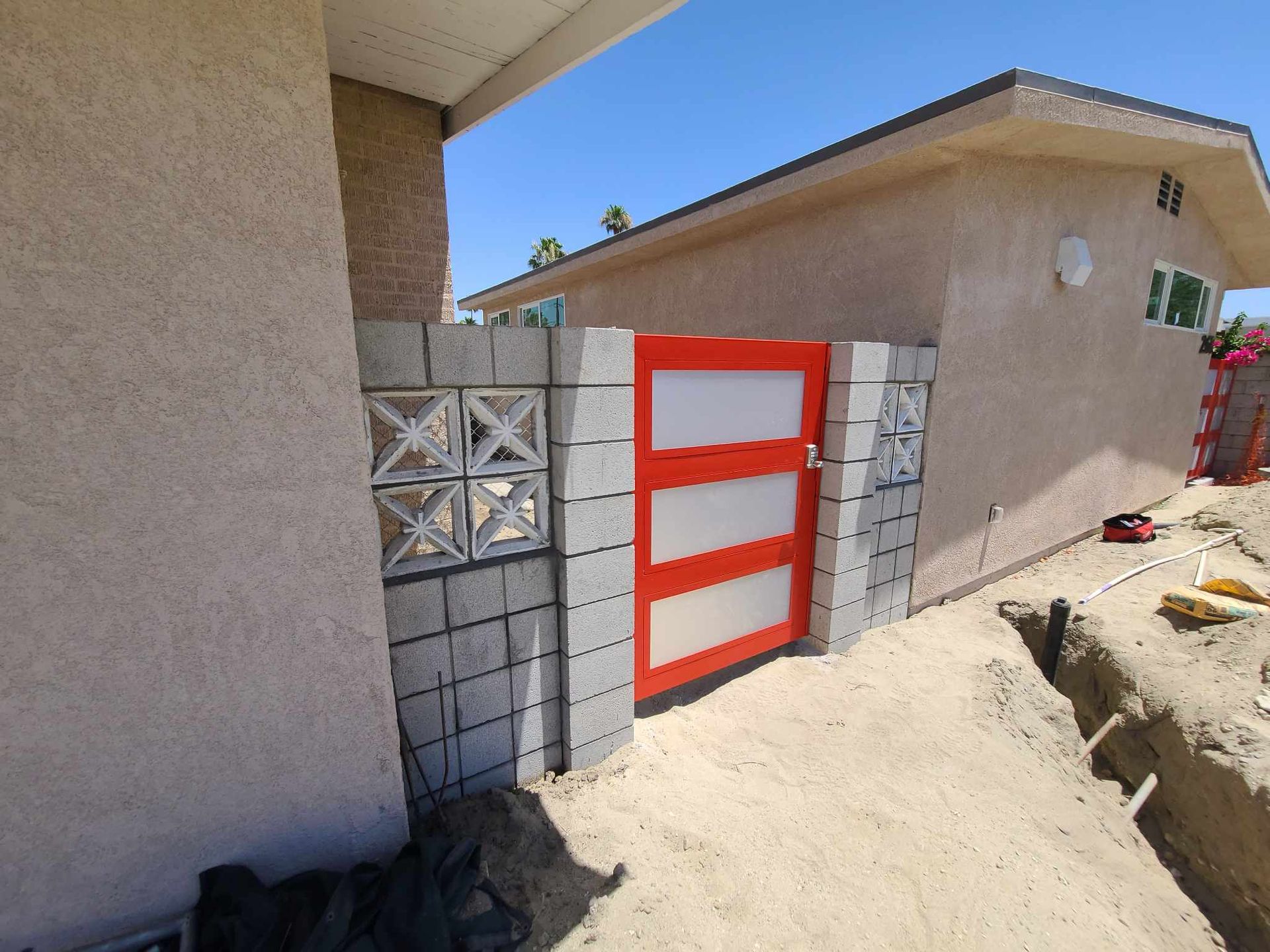 A brick wall with a red gate in front of a house