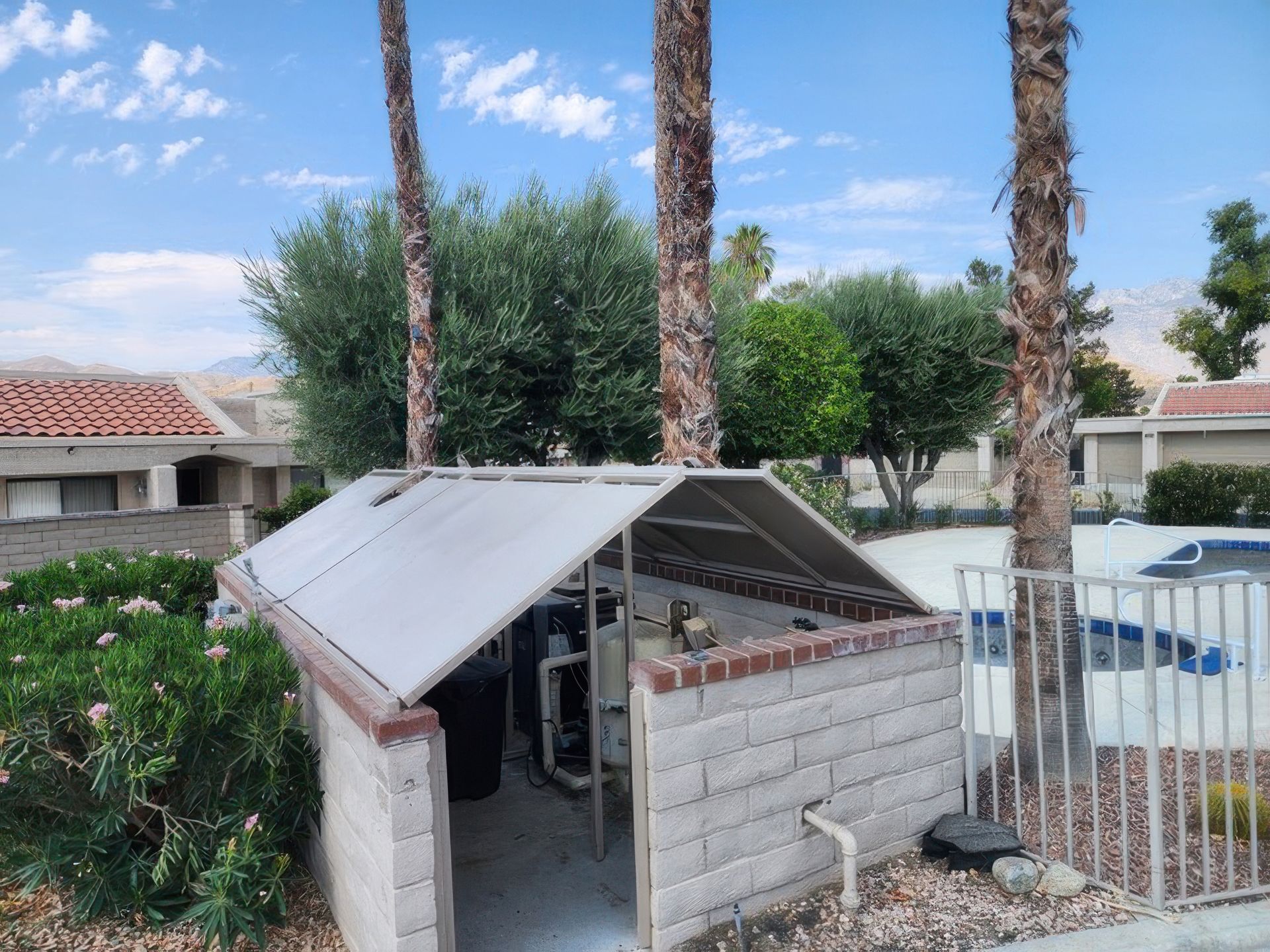 A shed with a roof is surrounded by palm trees