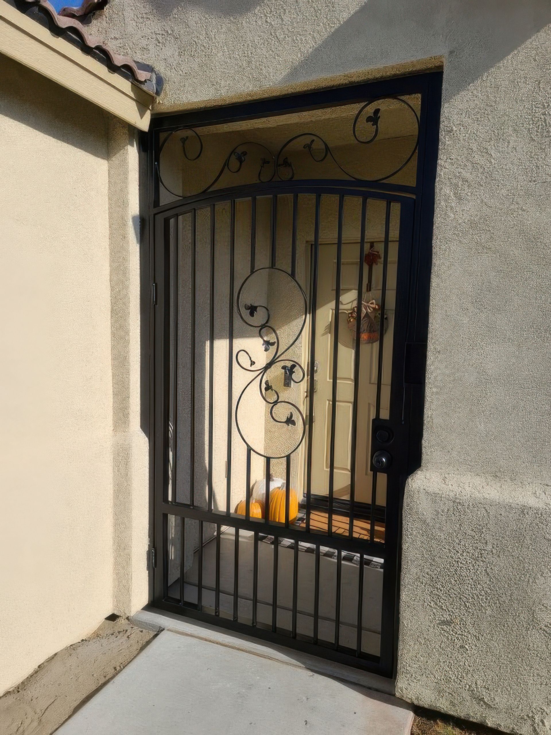 A wrought iron gate is on the side of a building