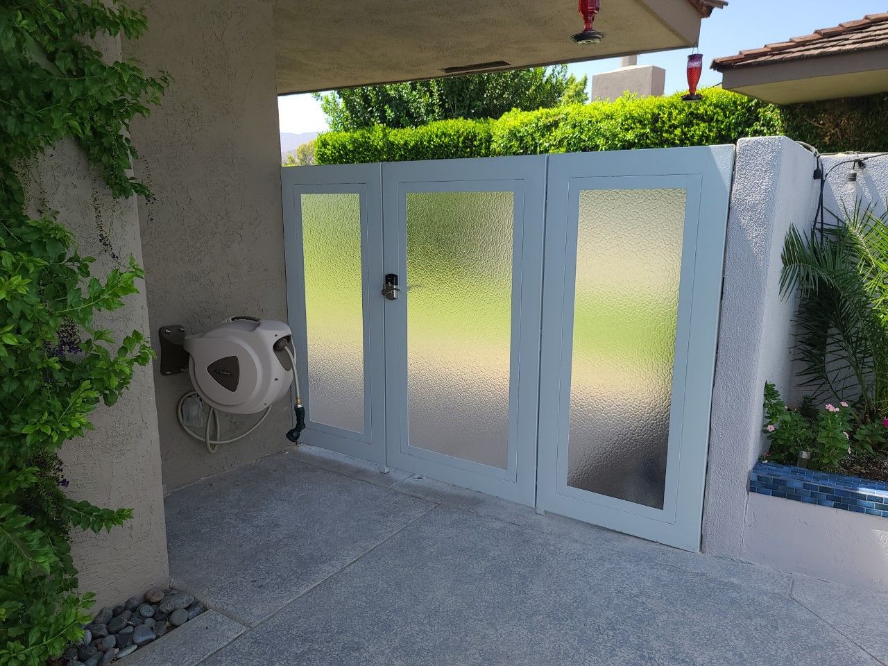 A white gate with frosted glass is in front of a house