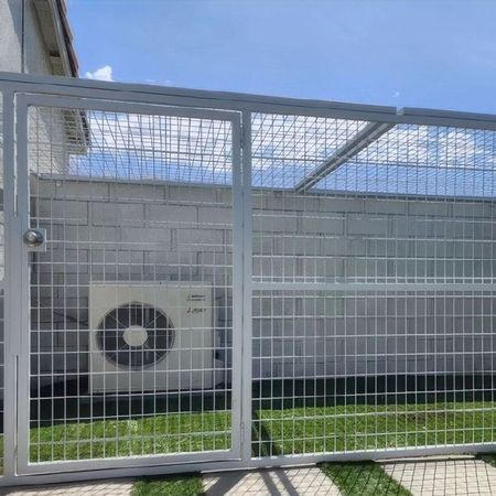 An air conditioner is behind a fence with a gate