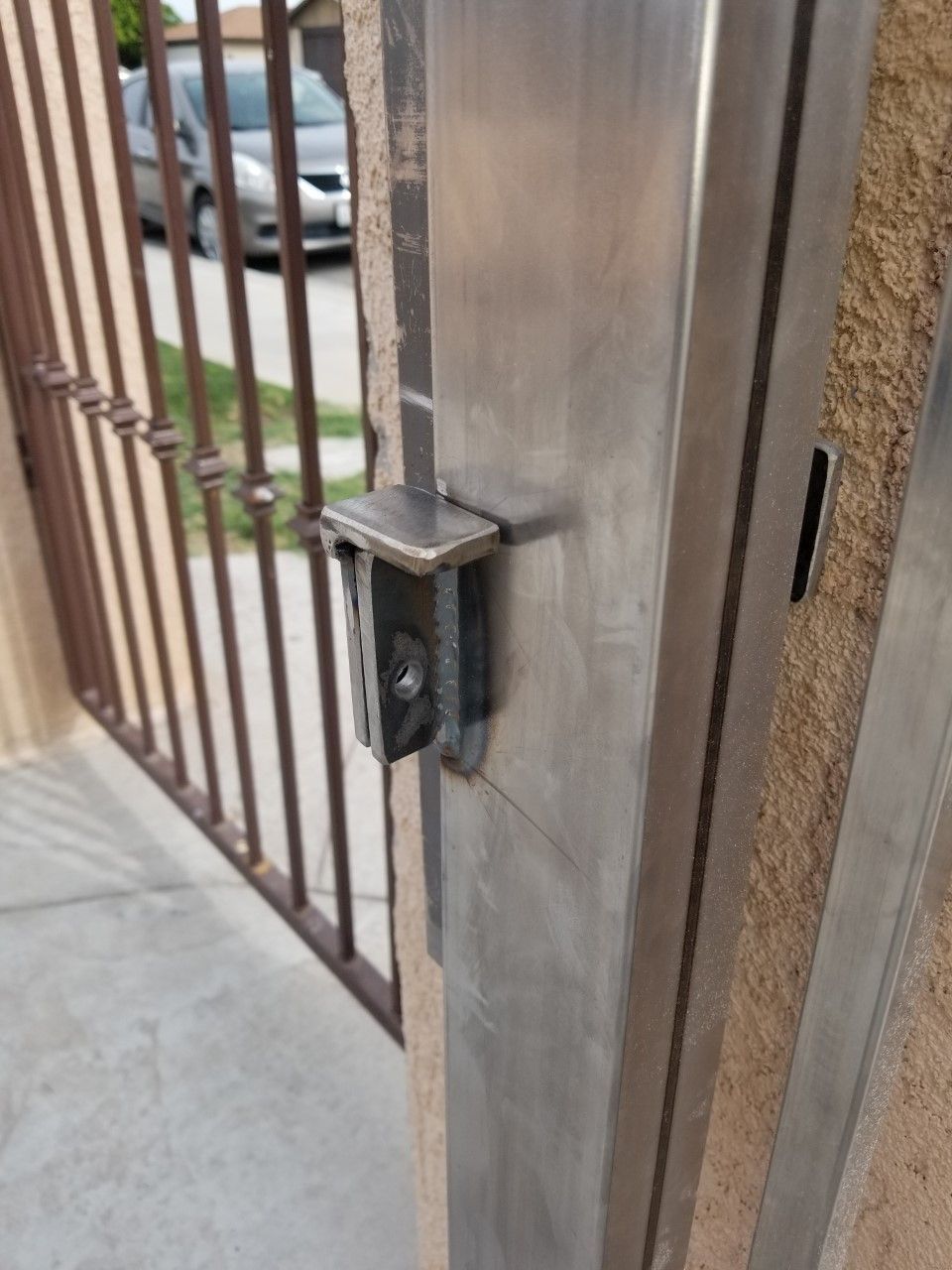 A close up of a metal gate with a car parked in the background