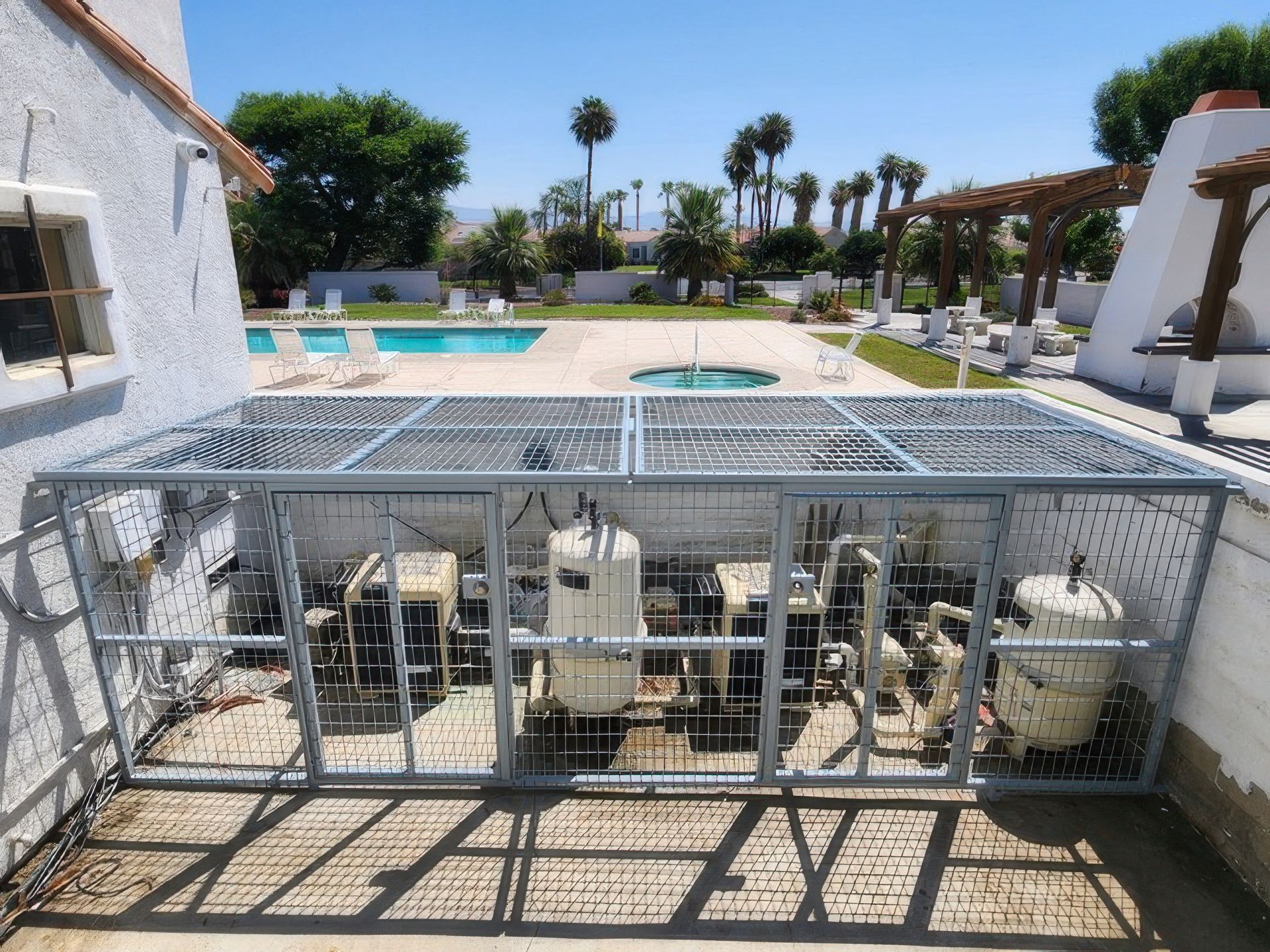 A metal cage with a pool in the background