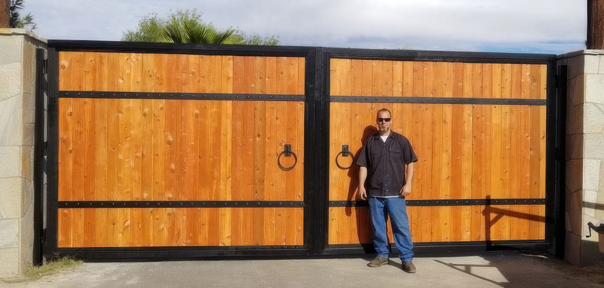 A man is standing in front of a wooden gate.