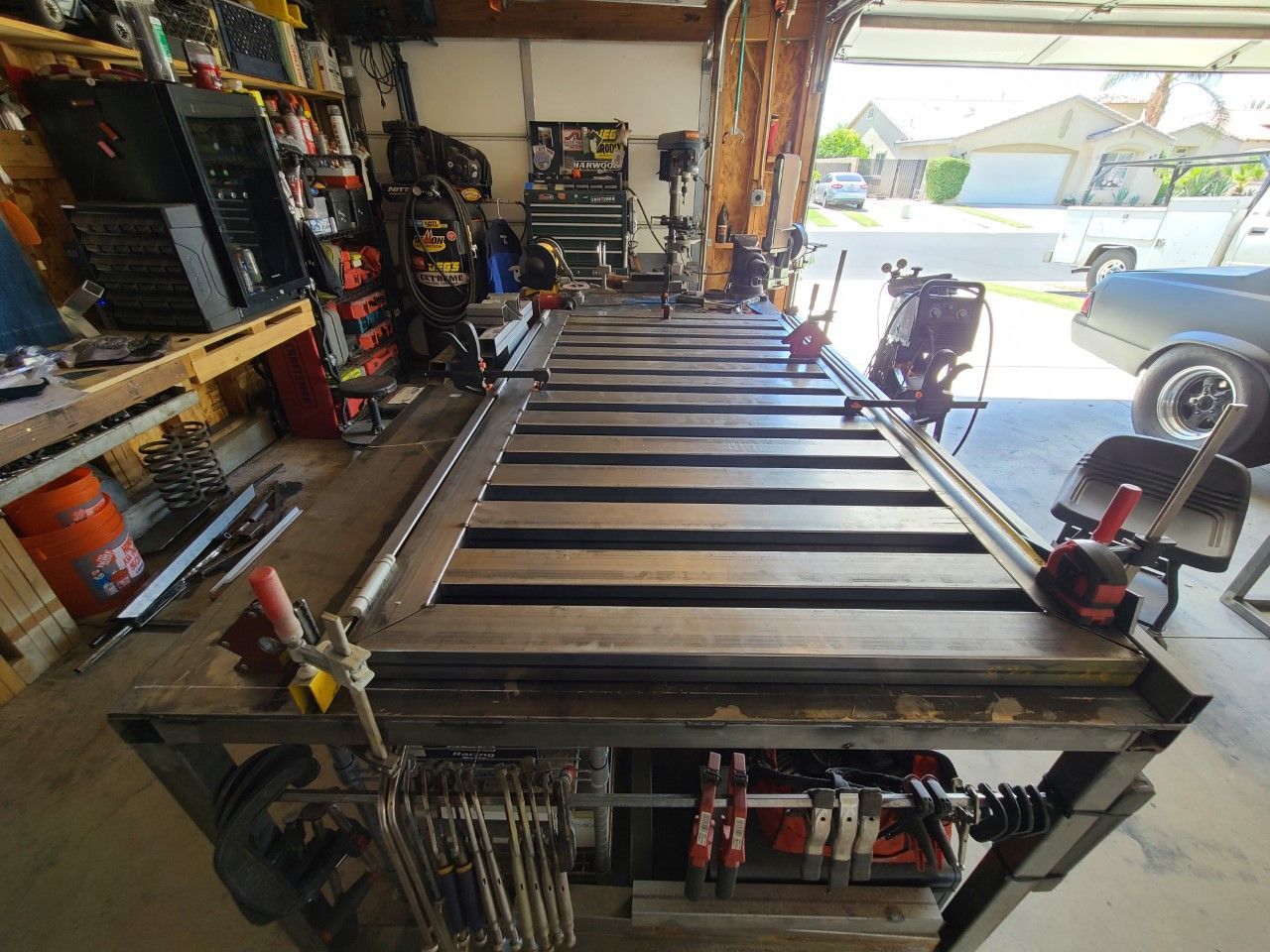 A metal table is sitting in a garage next to a car.