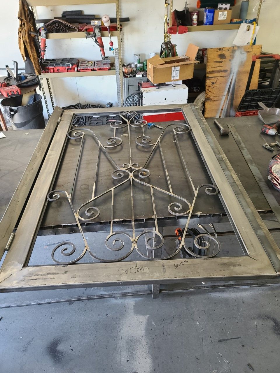 A wrought iron gate is sitting on a table in a garage.