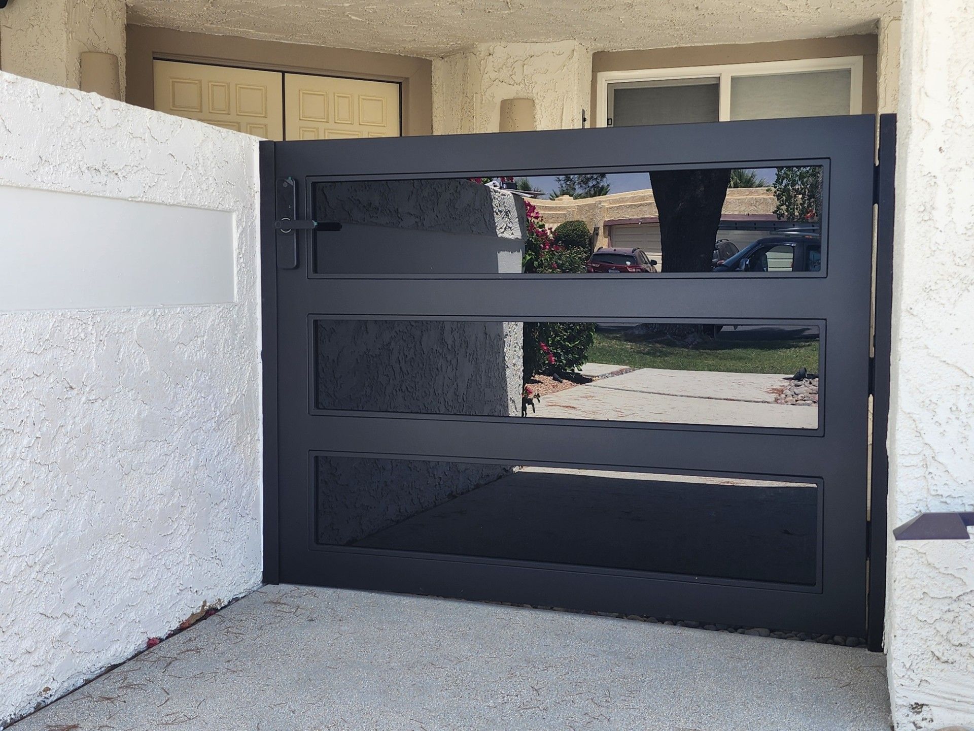 A black gate is sitting in front of a white wall.