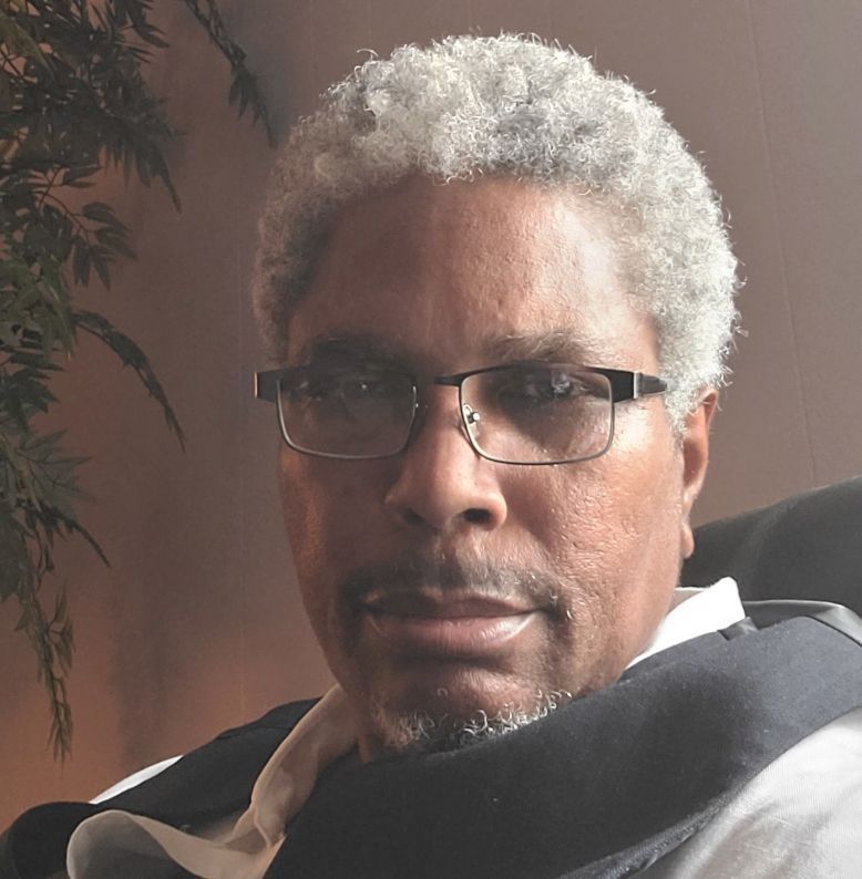 A man with glasses and a beard looks at the camera