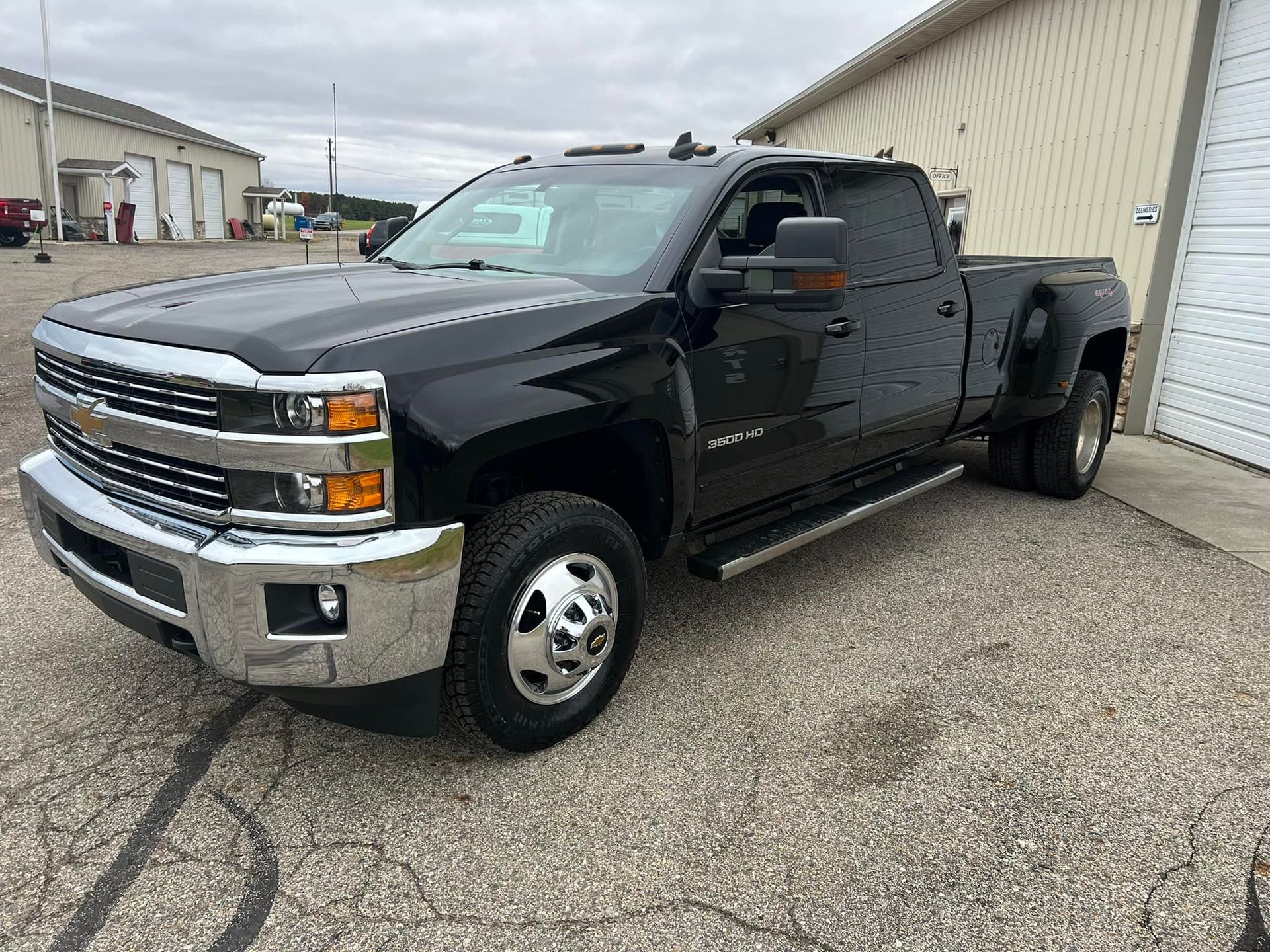 Black Chevrolet Silverado 3500HD pickup truck parked outside a building on an overcast day.