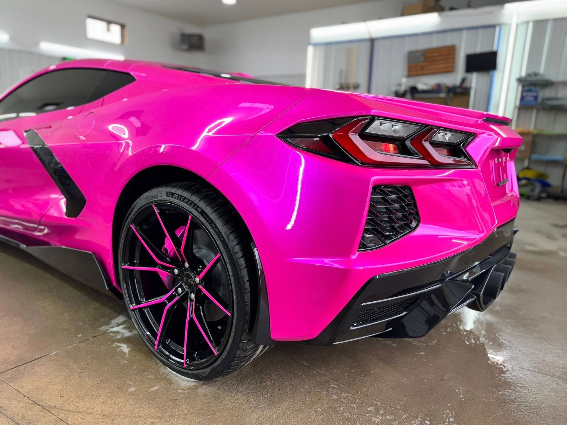 Pink Corvette with black accents, parked indoors.