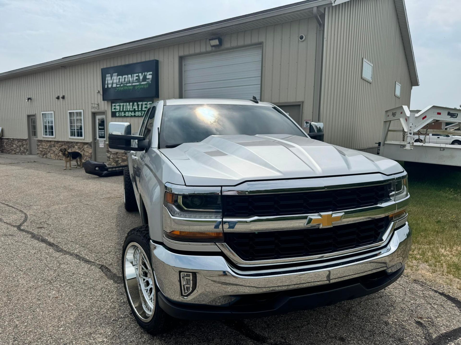 Silver Chevy truck parked in front of a business with a logo that reads 