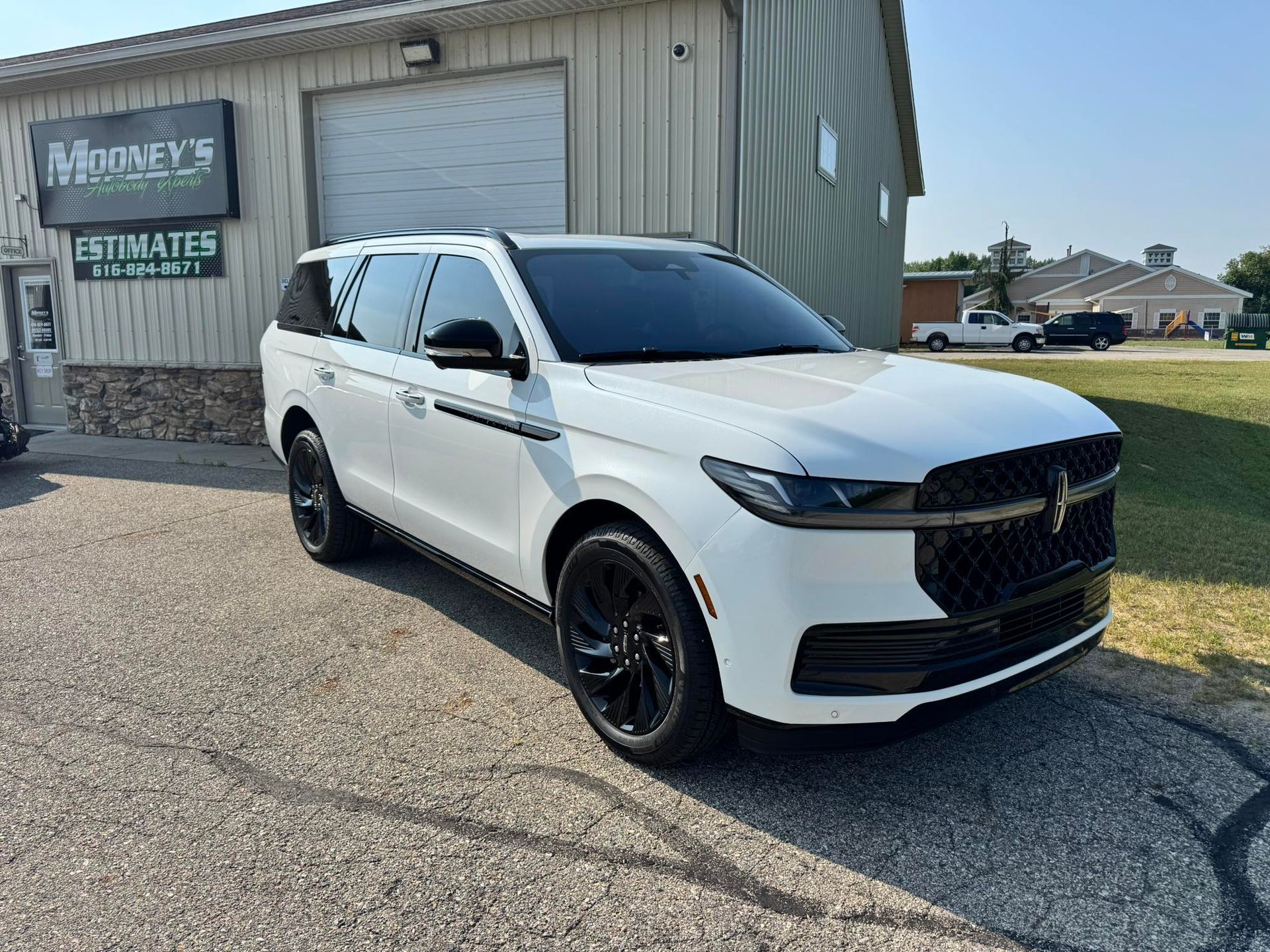 White Lincoln Navigator SUV parked in front of a business, black wheels, tinted windows.
