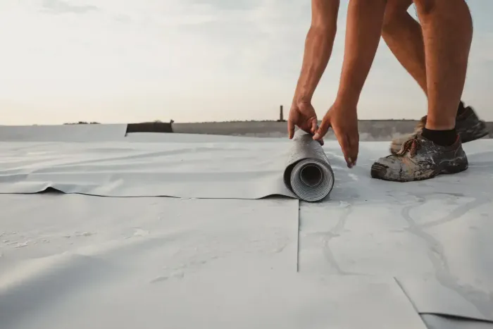 Contractor installing flat roofing membrane on commercial project