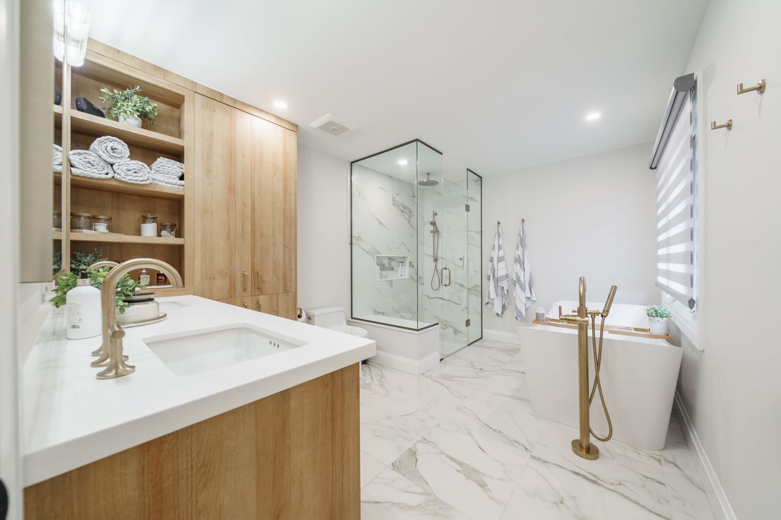Bright white modern bathroom with double sink, glass shower, and marble tile flooring